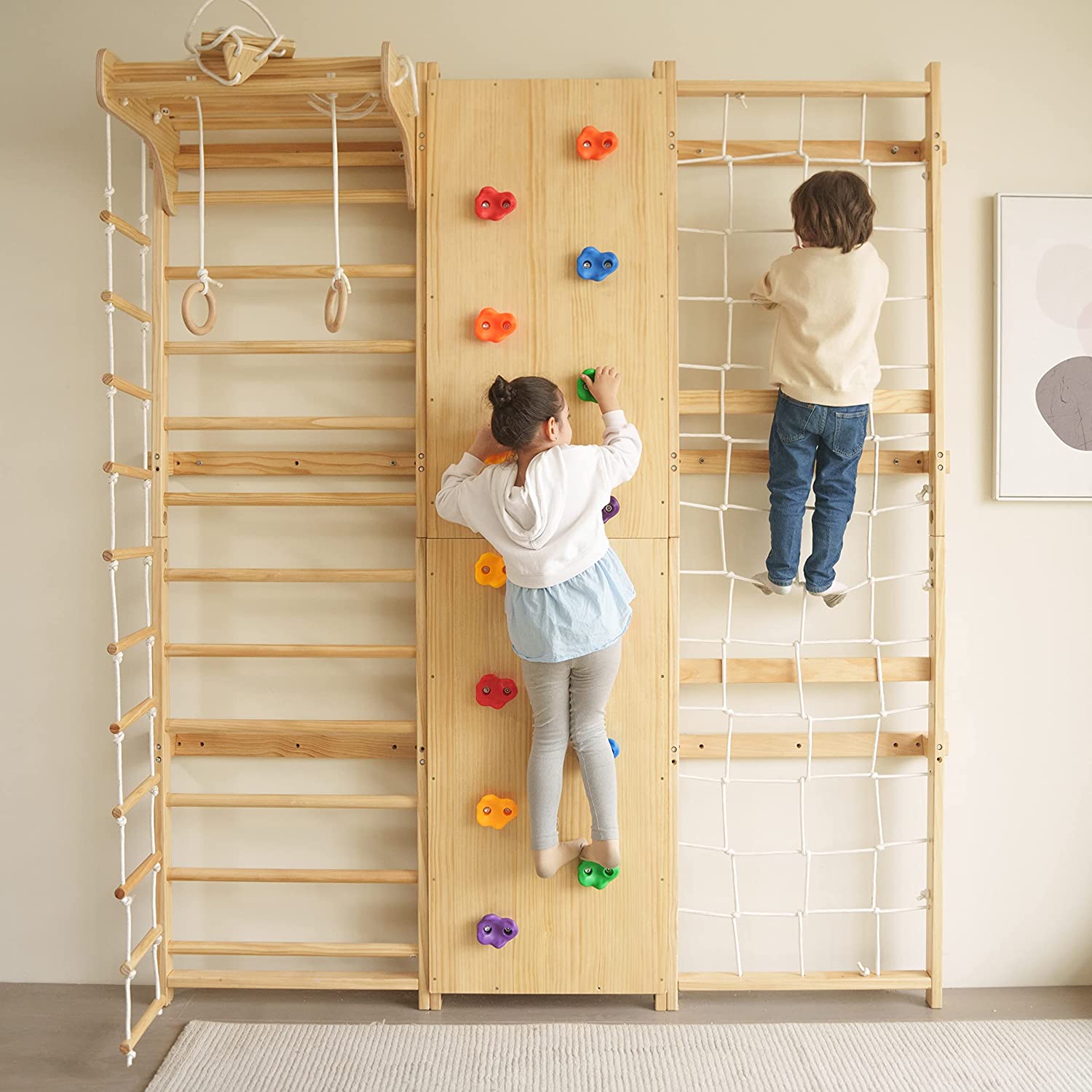 Two children are playing on the Walnut - 9-in-1 Swedish Ladder Wall Gym and Climber from PP AVENLUR. The solid wood structure includes a Swedish Ladder Wall Gym, a rope ladder, gymnastic rings, rock climbing holds, and a cargo net. The girl is climbing on the rock wall while the boy is scaling the cargo net.