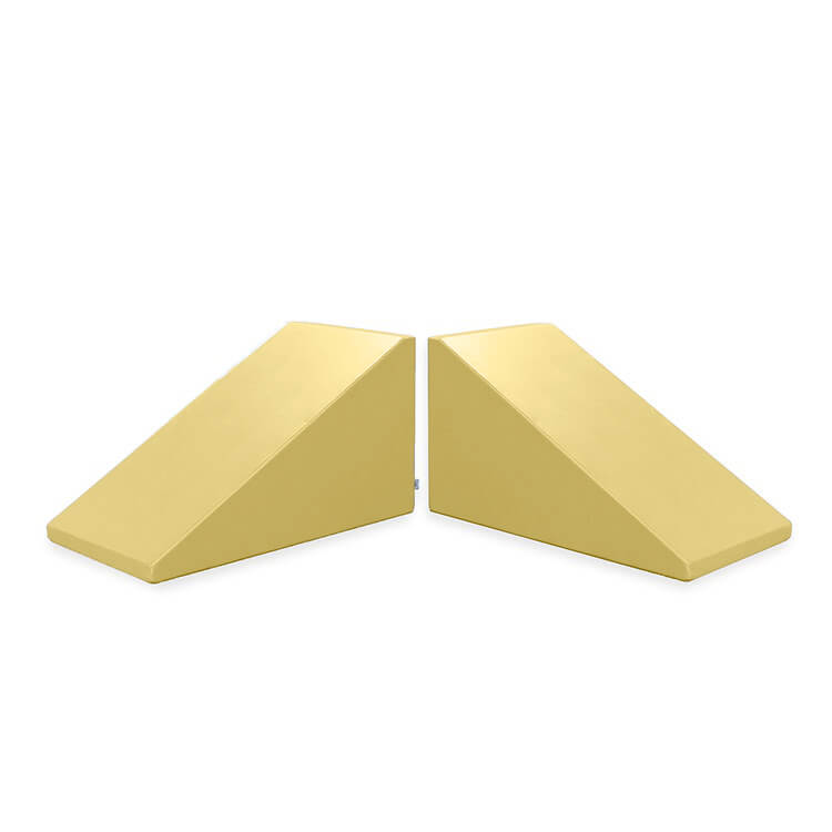 Two identical, light-yellow triangular wedge-shaped objects positioned side by side, mirroring each other with their slanted surfaces facing outward. The Mega Wedge Play Triangles by Foamnasium are a durable foam playset featuring straight edges and a flat base, ensuring both fun and safety for children during playtime.